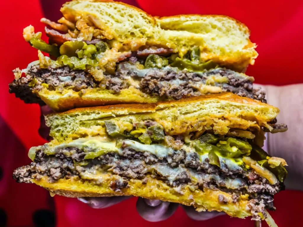 A massive, gourmet double cheeseburger, sliced in half to show its layered ingredients of beef, cheese, bacon, and jalapenos, a prime example of the best burgers near Richmond Road Farms