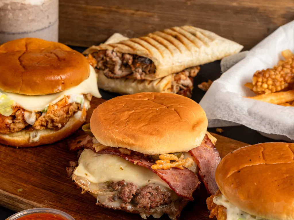 Tasty burgers from burger catering services near Waterford with fries, wraps, and milkshake on wood