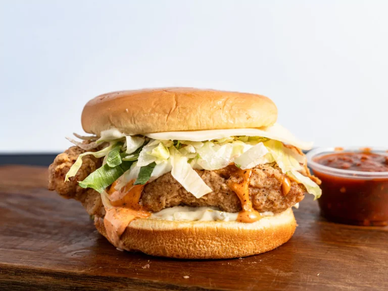 Crispy chicken burger from burger catering in Sugar Land with lettuce, sauce, and salsa on wood