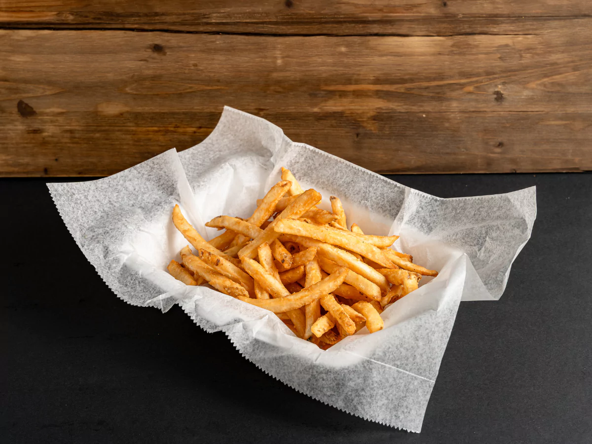 Golden fully loaded fries in Townewest presented in a lined basket against a wooden background