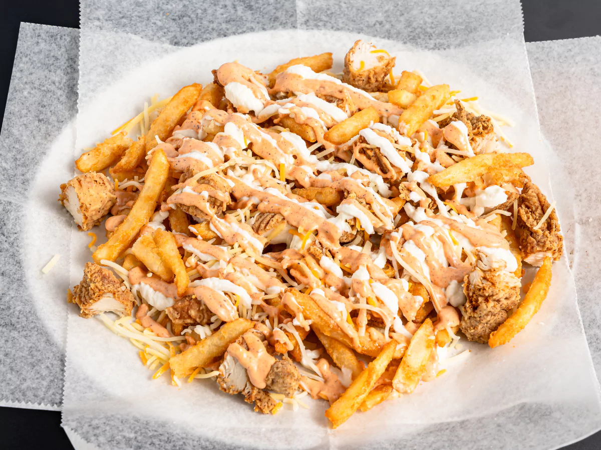 Tasty healthy chicken burger in Waterford featuring fries, chicken, and spicy sauce drizzles