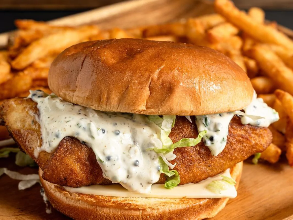 A delicious fish burger with crispy fried fish, creamy tartar sauce, fresh lettuce, and melted cheese, served with golden fries at local burger restaurants near Waterford