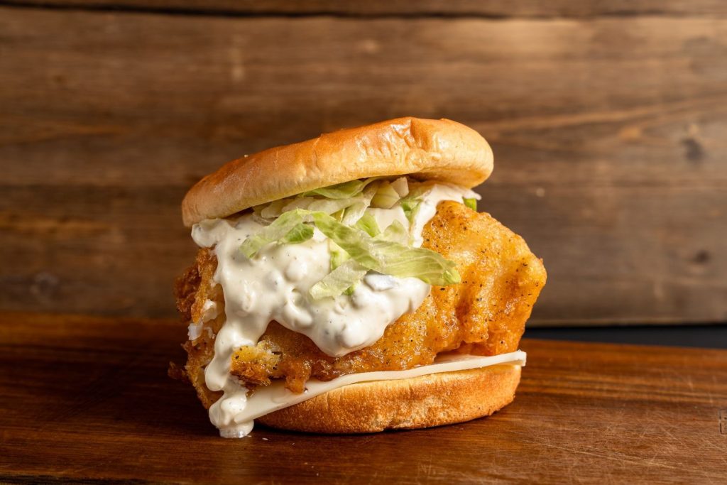 Crispy fish burger with creamy sauce and lettuce, served at top burger restaurants in Sugar Land.