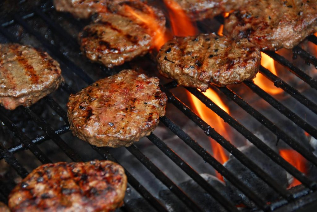 Juicy burgers grilling with flames, paired with loaded fries in Sugar Land for a tasty meal.
