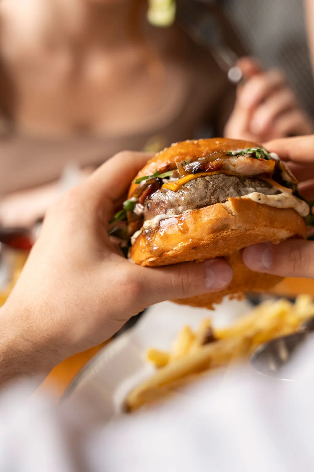 A person enjoying a tasty Halal burger with fries at a cozy eatery in Sugar Land.