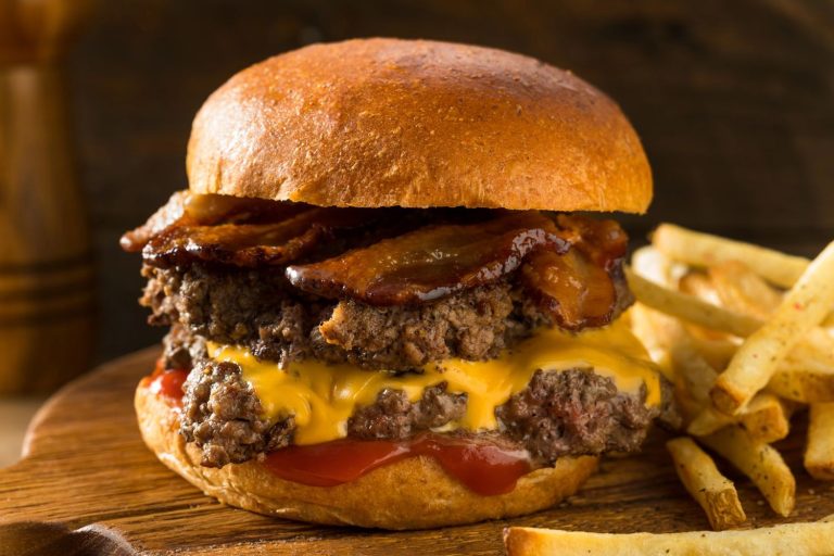 Mouthwatering late night burgers in Sugar Land with bacon, cheese, and fries, served on a wooden board.