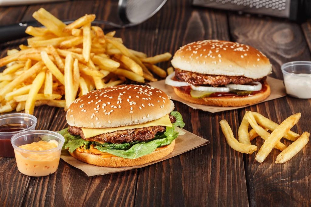 Delicious burgers with loaded fries in Sugar Land, served with dipping sauces on a rustic wooden table.
