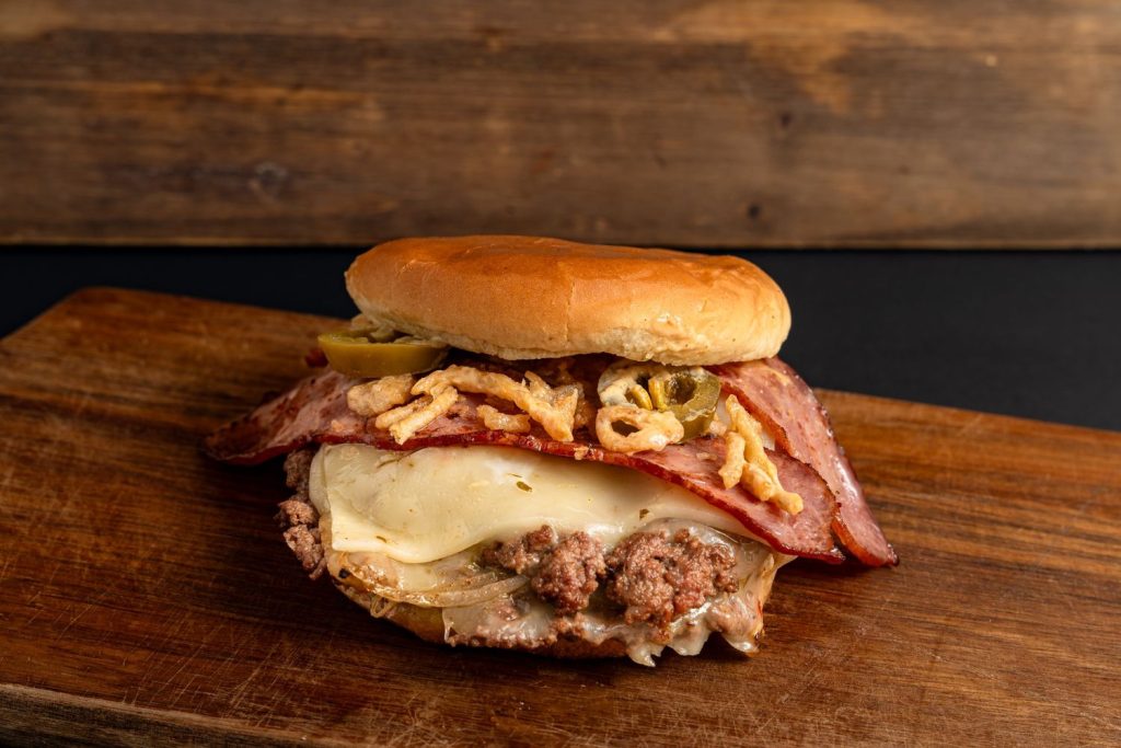 Hearty burger with melted cheese, bacon, jalapenos, and onion rings, ideal for burger catering in Sugar Land.