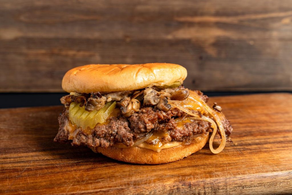 Savory double burger with melted cheese, mushrooms, onions, and pickles at top burger restaurants in Sugar Land.