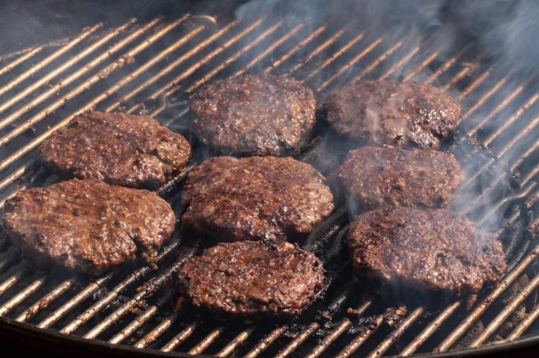 Sizzling affordable burgers on a smoky grill in Sugar Land, TX, featuring juicy beef patties with perfect sear marks for budget-friendly backyard feasts.