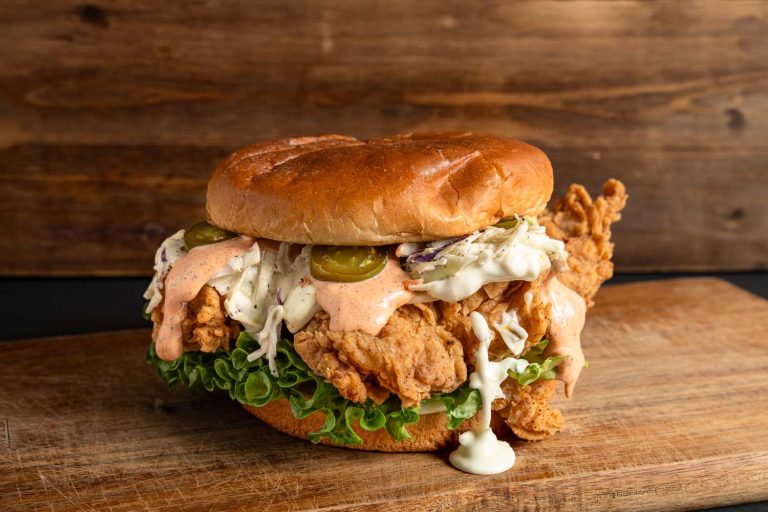 Juicy affordable burger with crispy chicken, coleslaw, and jalapenos on a bun, served in Sugar Land, TX.