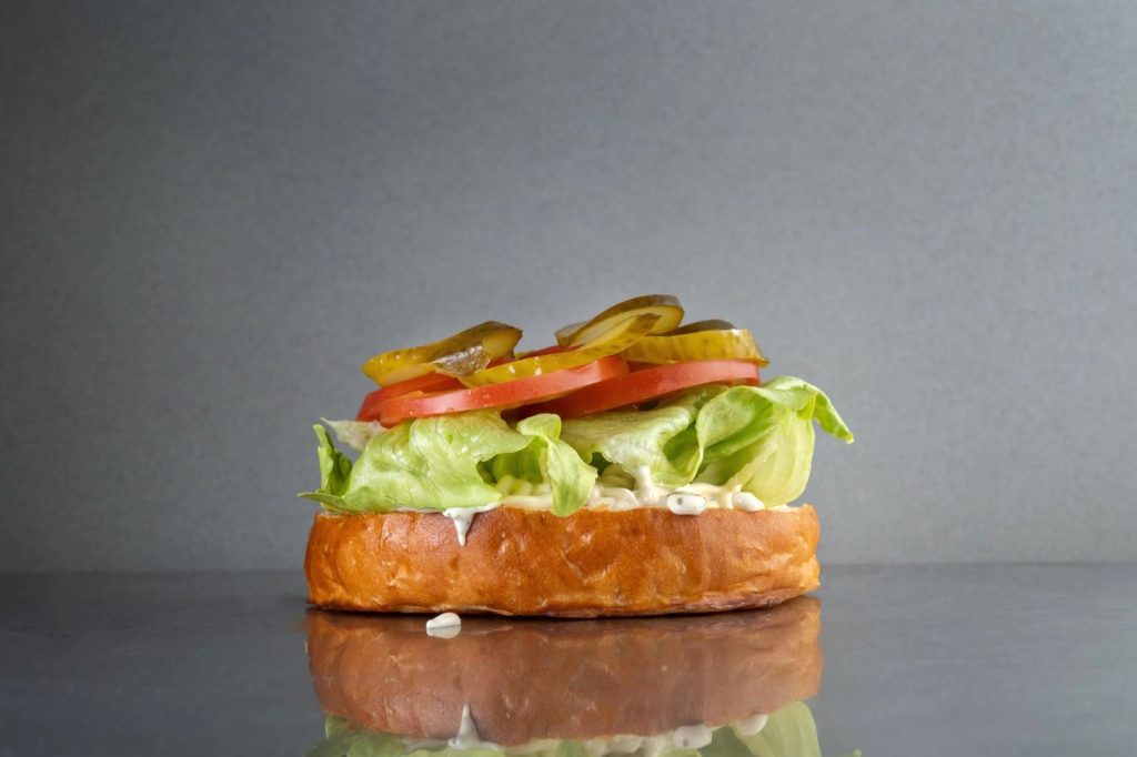 Fresh chicken burger with pickles, lettuce, and tomato on a bun, available in Sugar Land.