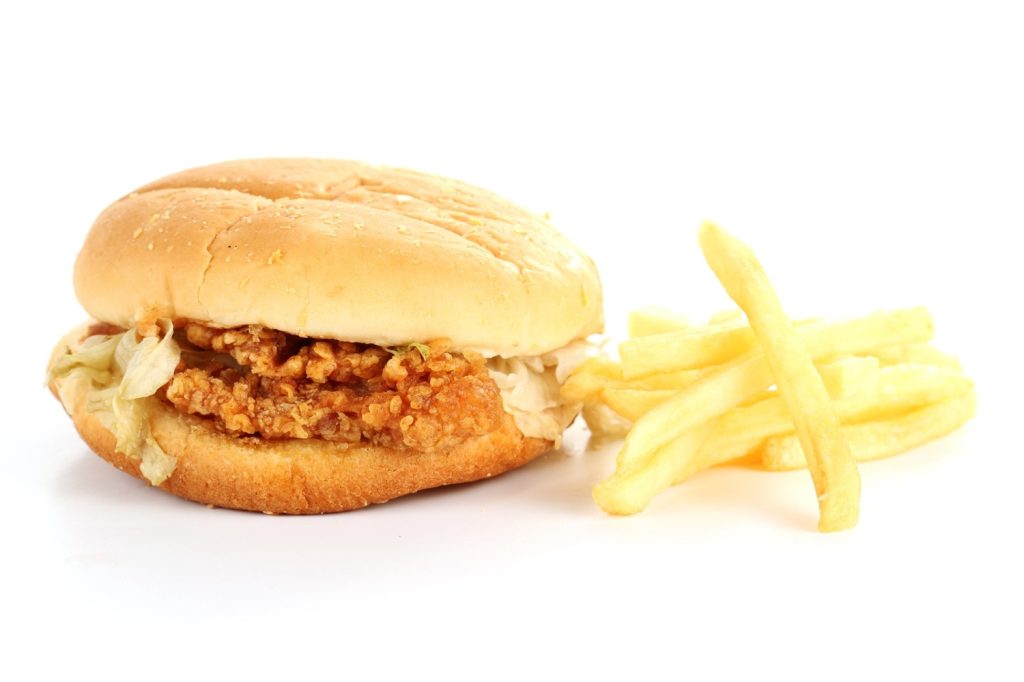 Golden fries served with crispy chicken burger Sugar Land featuring sesame bun and shredded lettuce in fast food promo.